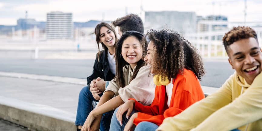 Groep multiculturele mensen zit op stoeprand