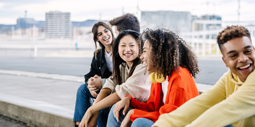 Groep multiculturele mensen zit op stoeprand